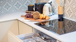 A kitchen counter with a toaster, a coffee maker, and a wooden cutting board with bread, grapes, and croissants. - Mouzinho 215 - Apartment 303 by LovelyStay (Porto)