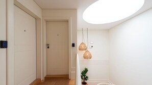 A modern hallway with a wooden floor, a white railing, and a potted plant. - Mouzinho 215 - Apartment 303 by LovelyStay (Porto)