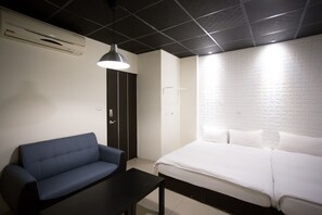 Une chambre d’hôtel avec un lit, un canapé bleu, une petite table et un plafond noir.
