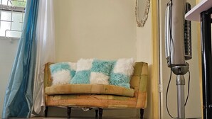 Una habitación con un sofá, un ventilador de pie y una alfombra estampada.