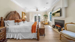 Un dormitorio amplio con una cama grande, una chimenea, un sofá y vistas al exterior.