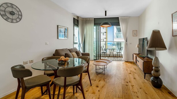 Un salon moderne avec une table à manger en verre, des canapés confortables et une grande fenêtre donnant sur la ville.