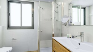Une salle de bain moderne équipée d’une douche, de toilettes et d’un meuble-lavabo.