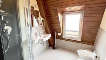 A modern bathroom with a glass shower enclosure, a white sink, and a toilet.