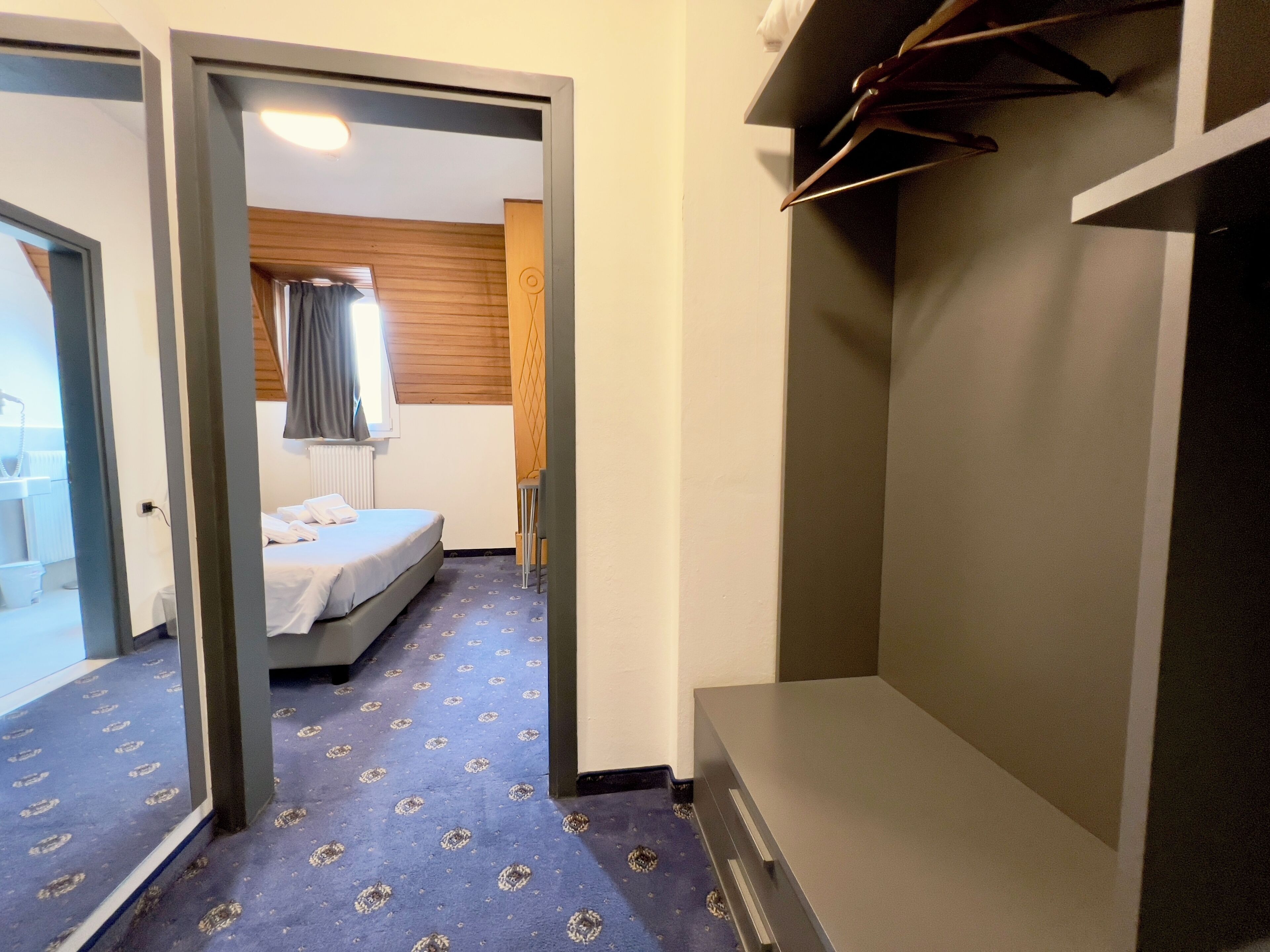 Et hotelværelse med en seng, et klædeskab og et spejl.