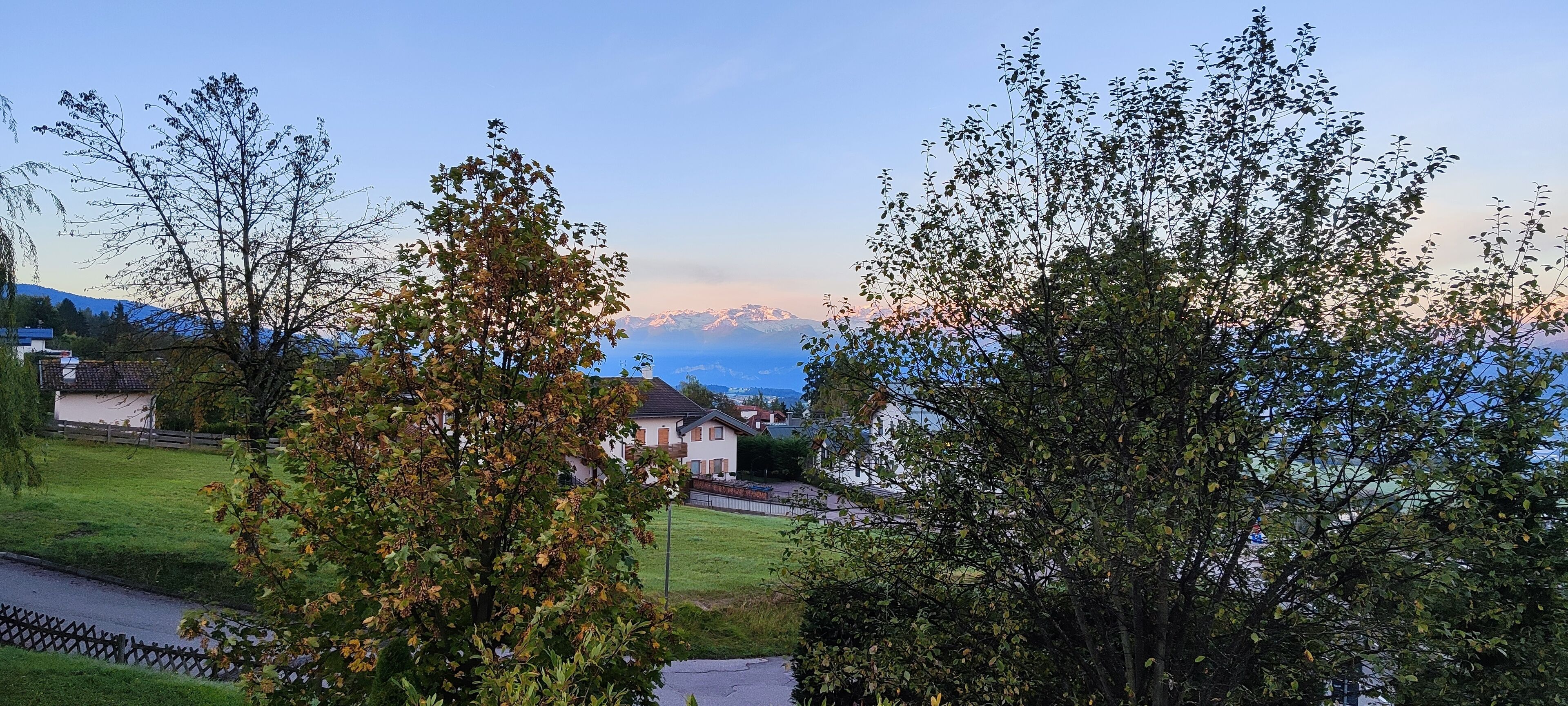 Ett bostadsområde med hus, en gräsyta och en utsikt över berg i bakgrunden.
