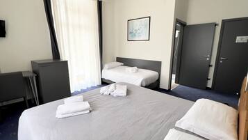 Camera d'albergo con due letti, una scrivania, un armadio e una finestra con tende.