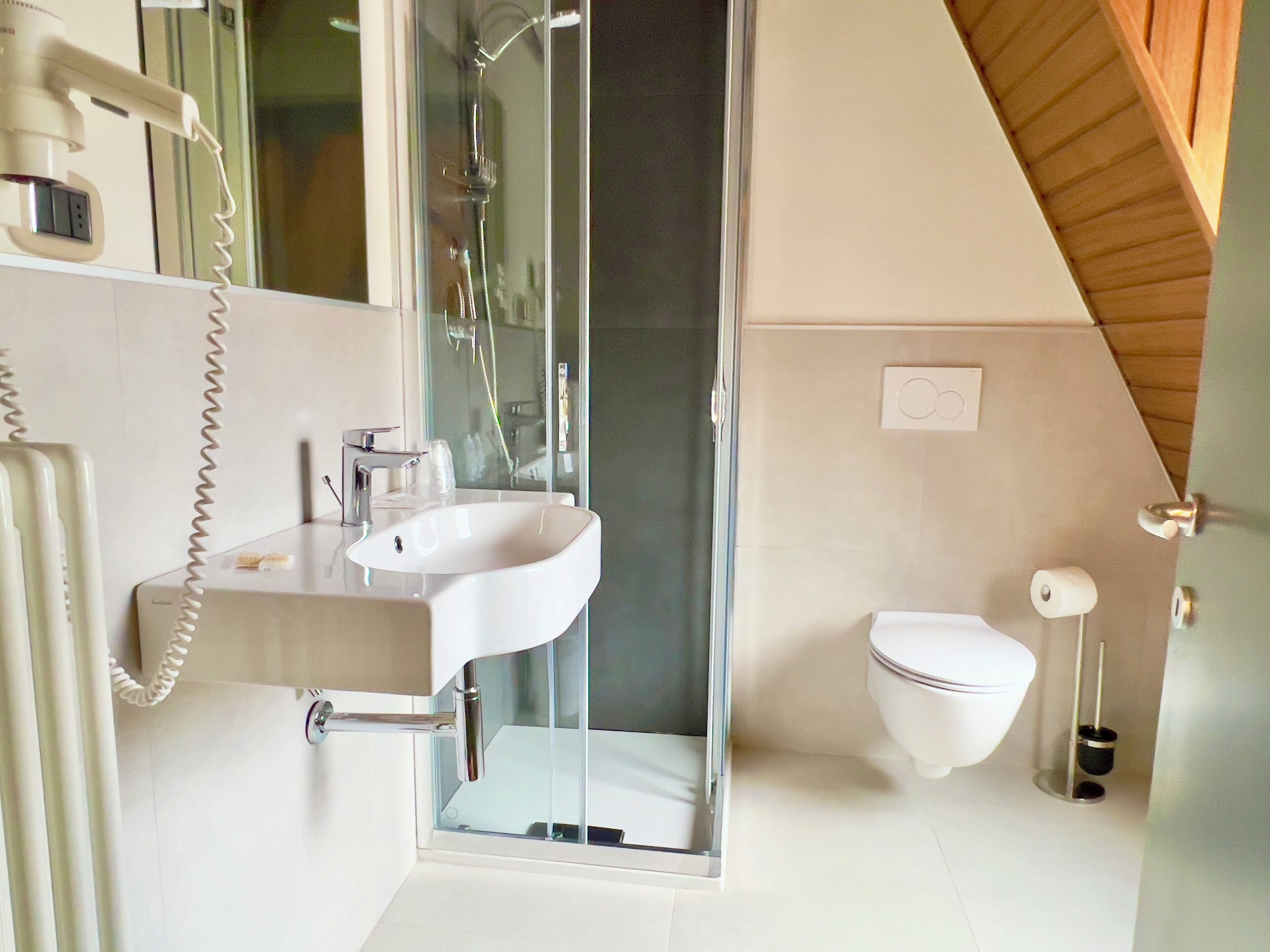 Ein modernes Badezimmer mit einer Duschkabine aus Glas, einem weißen Waschbecken und einer Toilette.