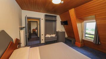 Ett hotellrum med en säng, ett skrivbord, en stol, en garderob, en tv och ett fönster med utsikt.