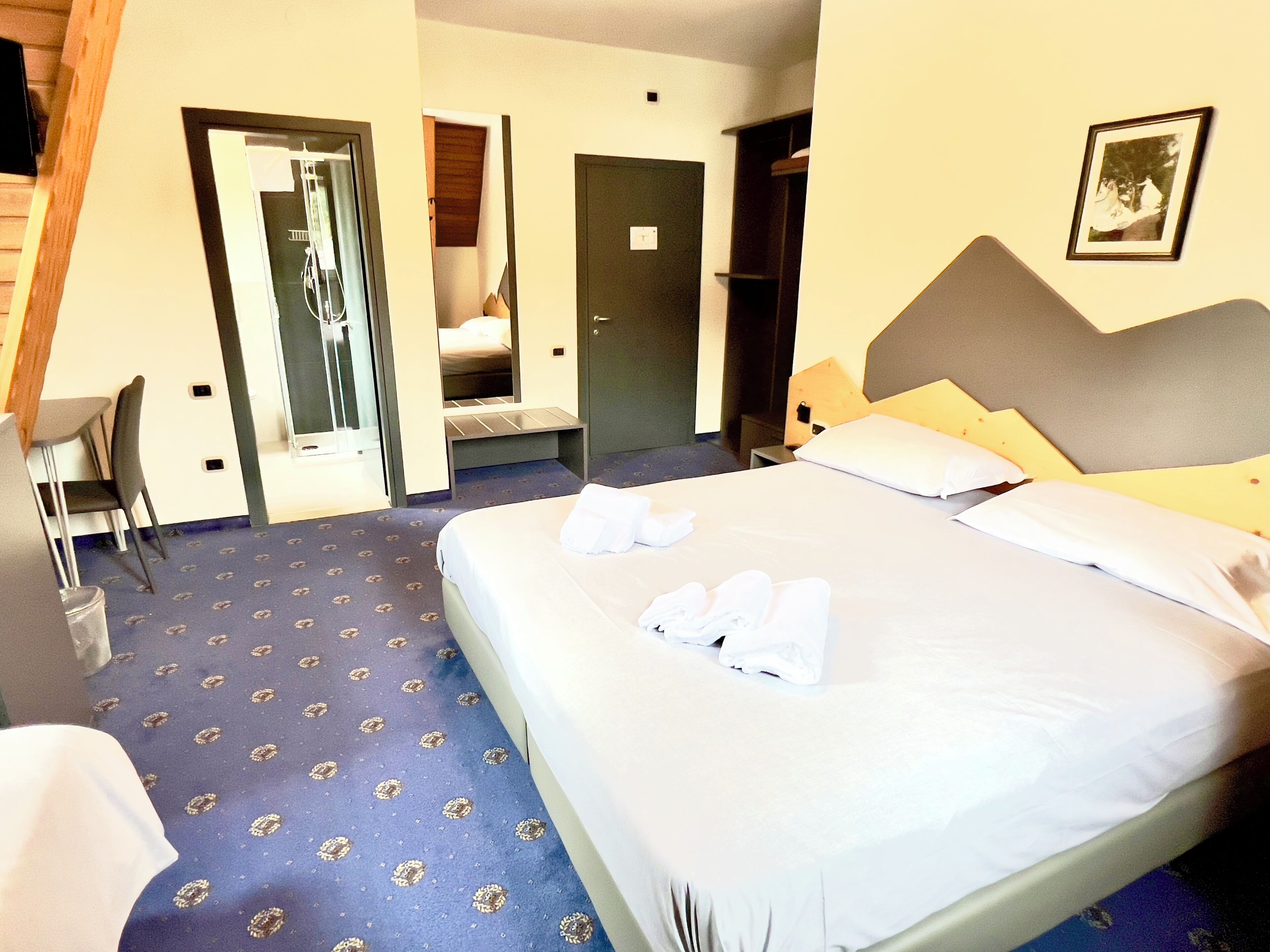 A hotel room with a bed, a desk, and a chair. There is a door leading to a bathroom and a closet.