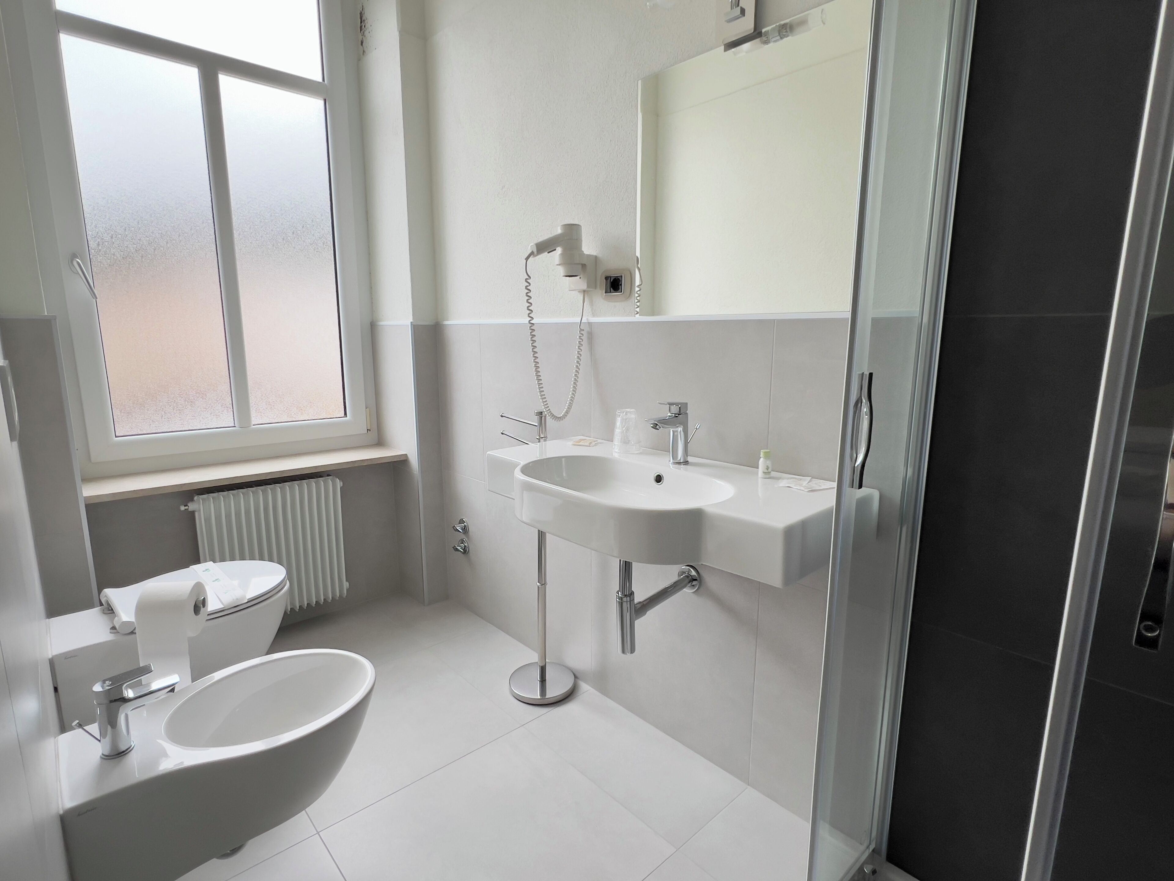 Ein modernes Badezimmer mit Toilette, Bidet und Waschbecken.