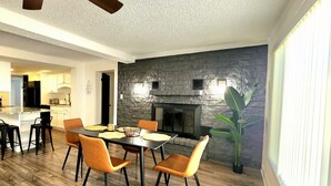 Ein moderner Essbereich mit einer Wand aus Stein, einem Kamin und einer großen Pflanze.