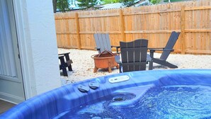 Ein Whirlpool mit Bedienfeld, eine Holzlattenumzäunung und Gartenmöbel.