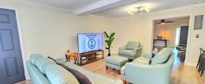A living room with a TV, two armchairs, a small table, and a plant.