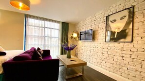 Ein modernes Zimmer mit Backsteinwand, einem Bett, einem Schreibtisch und einem an der Wand befestigten Fernseher.