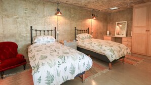 Ein Schlafzimmer mit zwei Betten, einem roten Sessel, einem Holzschrank und einem Spiegel.