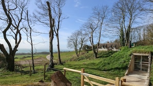 Ländliche Landschaft mit einem hölzernen Tor, einem Haus mit Strohdach und Blick auf das Meer.