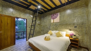 A bedroom with a large bed, wooden ceiling beams, a ladder, a nightstand with a lamp, and a painting on the wall. - The Wishes Hotel At Chiangmai Chiang Mai (Chiang Mai)