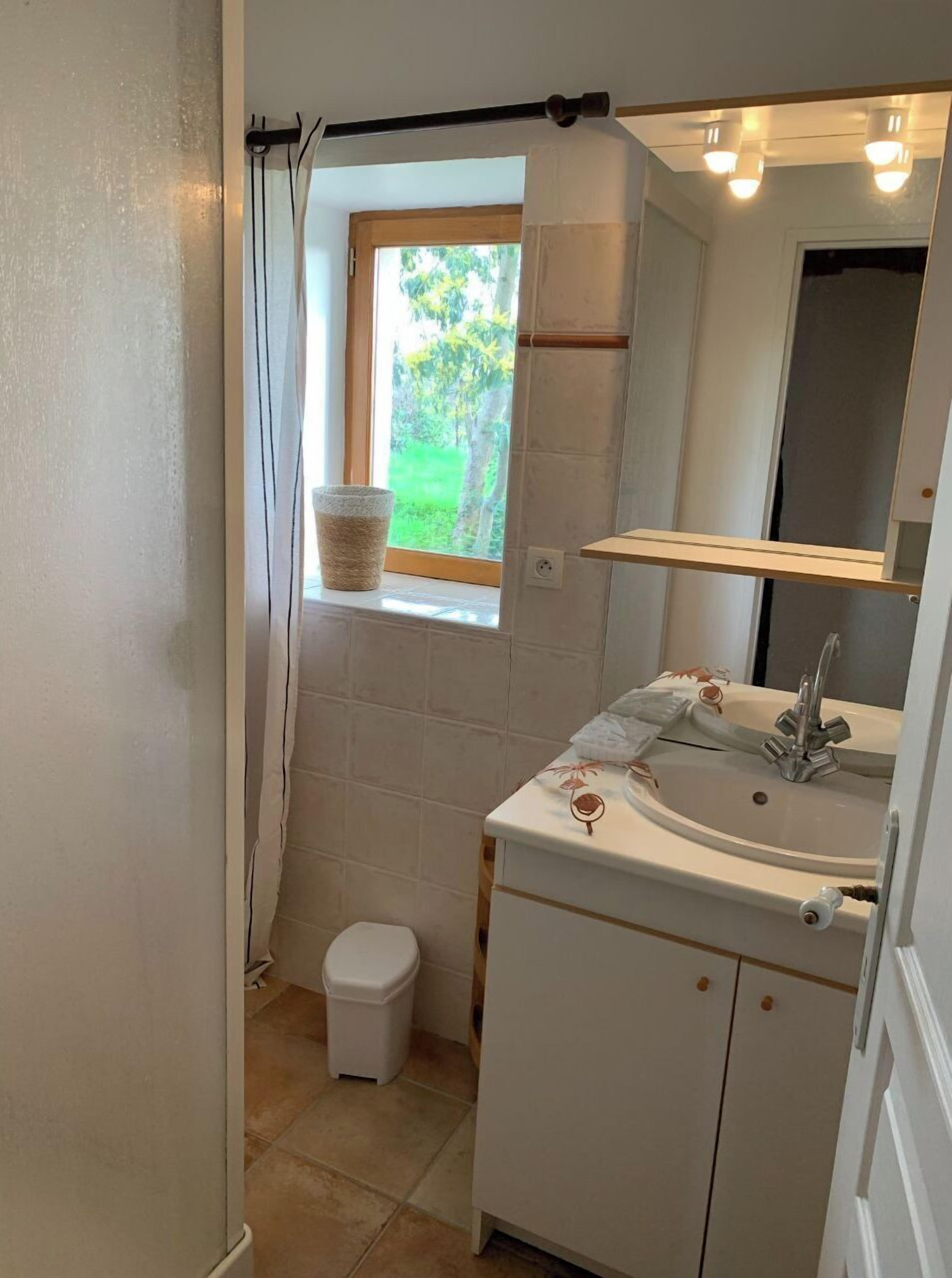 A small bathroom with a window, a sink, and a toilet.