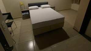 A bedroom with a bed, a nightstand, a wall-mounted picture, and a window with curtains. - Light Motel (Guarulhos)
