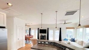 A modern kitchen with a granite countertop, white cabinetry, and a dining area with wooden chairs. - Bluefin - Amazing Panoramic Sea, Bridge, Bay Views! (Freeport)