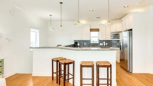 A modern kitchen with a central island, bar stools, pendant lighting, and stainless steel appliances. - Bluefin - Amazing Panoramic Sea, Bridge, Bay Views! (Freeport)