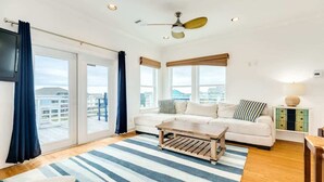 A spacious living room with a large window, a ceiling fan, and a striped rug. - Bluefin - Amazing Panoramic Sea, Bridge, Bay Views! (Freeport)