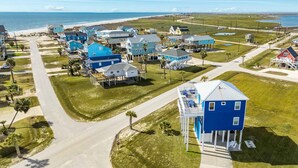 A coastal residential area with houses featuring blue exteriors, a beach in the background, and a clear sky. - Bluefin - Amazing Panoramic Sea, Bridge, Bay Views! (Freeport)