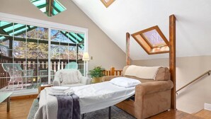 A cozy bedroom with a skylight, a bed, a chair, and a view of the outdoors. - Cottage on Rush - Heart of Fayetteville (Fayetteville)