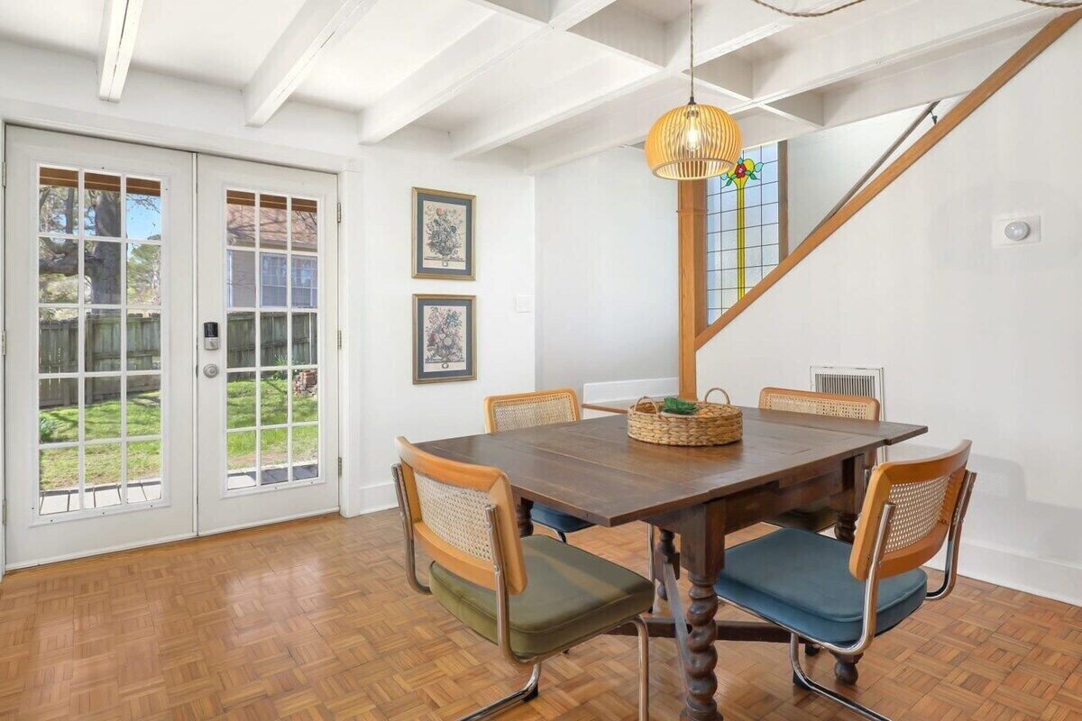 A dining area with a wooden table, six chairs, and a chandelier.