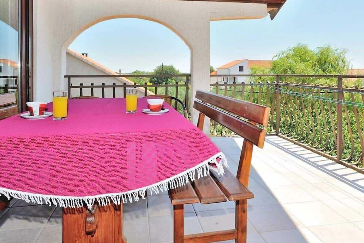 A covered outdoor dining area with a table, chairs, and a bench.