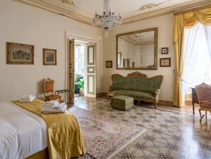 A room with a bed, a sofa, a chair, a mirror, and a chandelier. - Dimora Leone, a spacious luxury apartment in the heart of Lucca (Lucca)