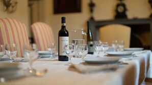 A dining table set with wine glasses, plates, and cutlery, with a bottle of wine in the center.