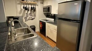 A modern kitchen with stainless steel appliances, a granite countertop, and white cabinetry.