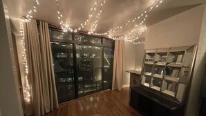 A room with a wooden floor, a glass door leading outside, and a bookshelf with multiple shelves.