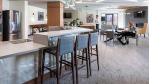 A modern kitchen with stainless steel appliances, a central island with bar stools, and a dining area with a large table and chairs.