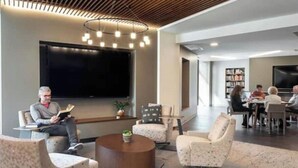 A modern lounge area with seating, a coffee table, and a flat-screen TV.