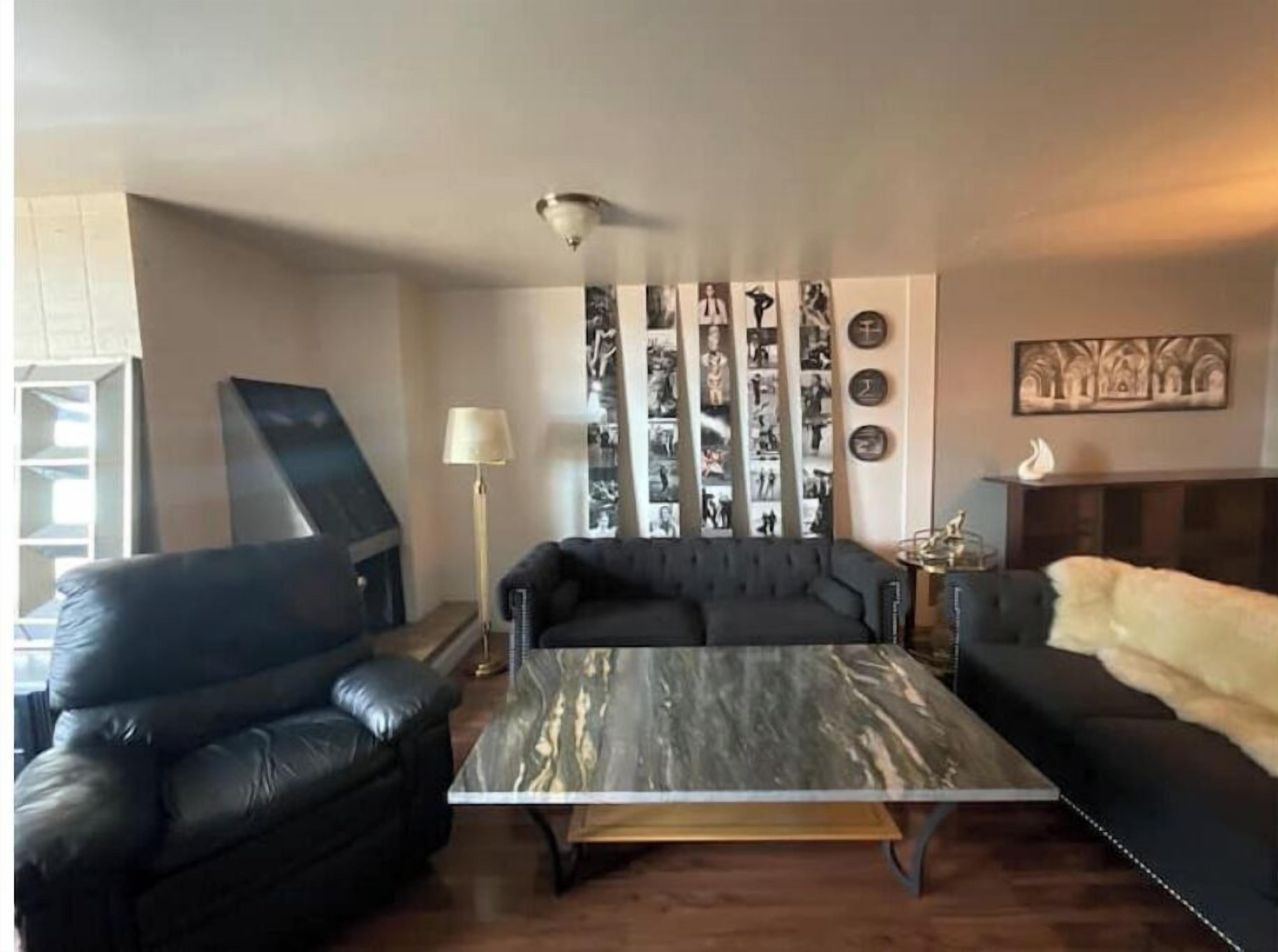 A living room with a black sofa, a coffee table, and a fireplace.