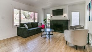 Un salon avec une cheminée, un canapé, une table basse et un téléviseur fixé au-dessus de la cheminée.