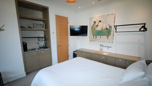 A hotel room with a bed, a TV mounted on the wall, a painting of a cow, and a wooden cabinet with a sign above it. - Private Modern Suite 15min from YVR self check in (Richmond)