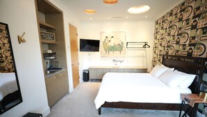 A hotel room with a large bed, a desk, a chair, a TV, and a kitchen area with a sink and cabinets. - Private Modern Suite 15min from YVR self check in (Richmond)
