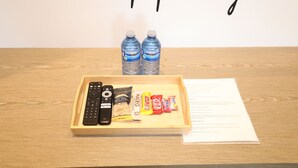 A wooden tray with a remote control, snacks, and bottled water on a table. - Private Modern Suite 15min from YVR self check in (Richmond)