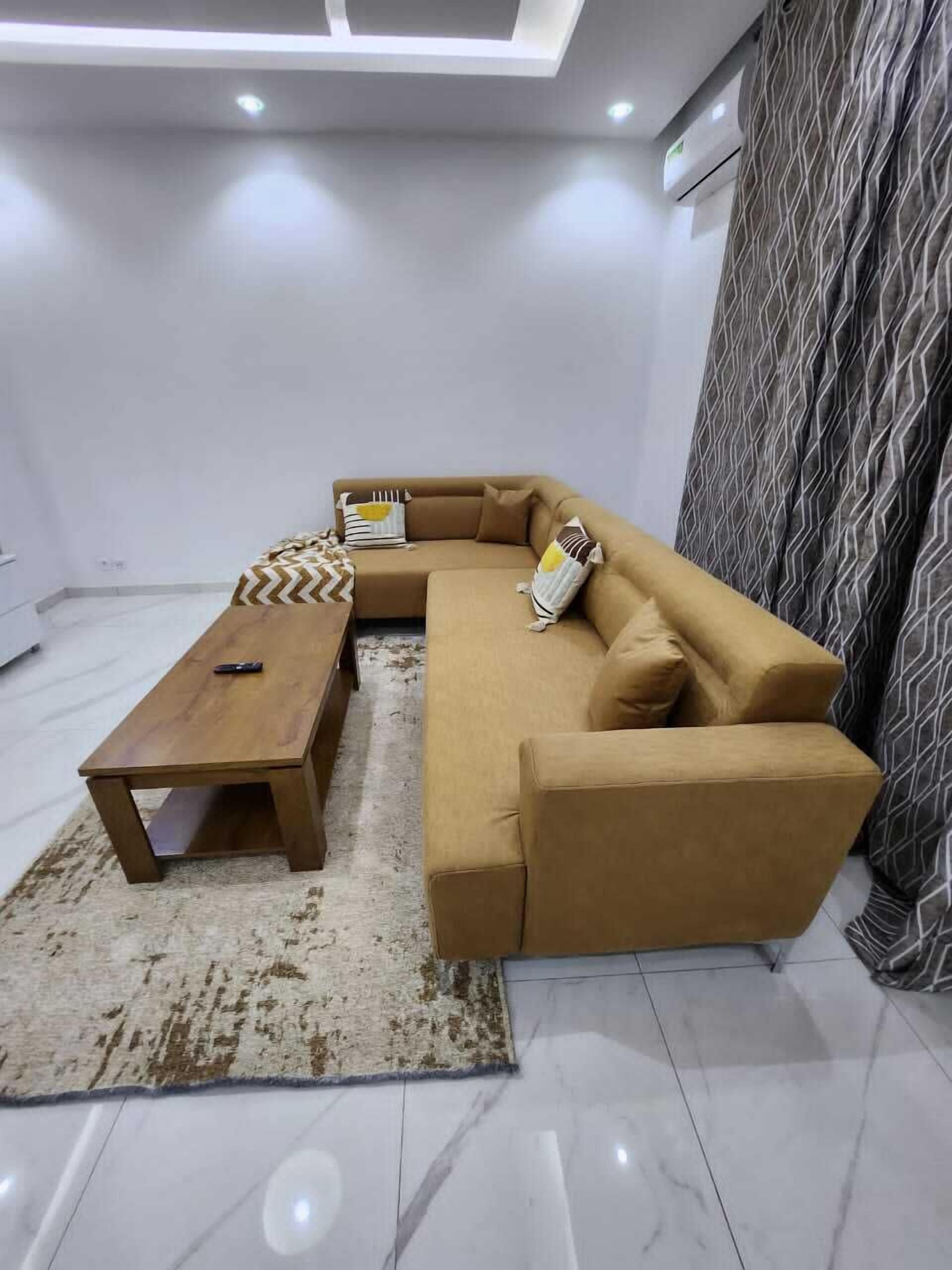 Una sala de estar moderna con un sofá modular, una mesa de centro de madera y una alfombra estampada.