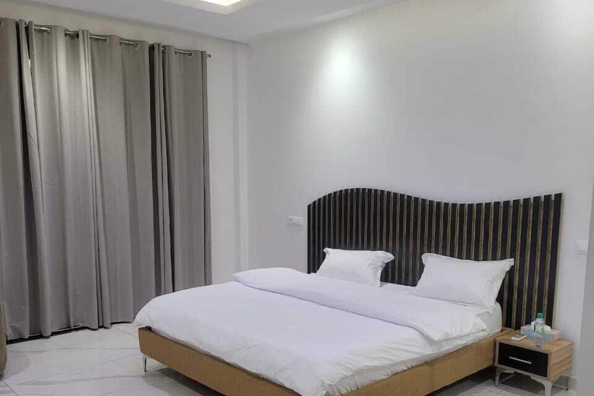 Quarto moderno com uma cama grande, uma mesa de cabeceira e um lustre.