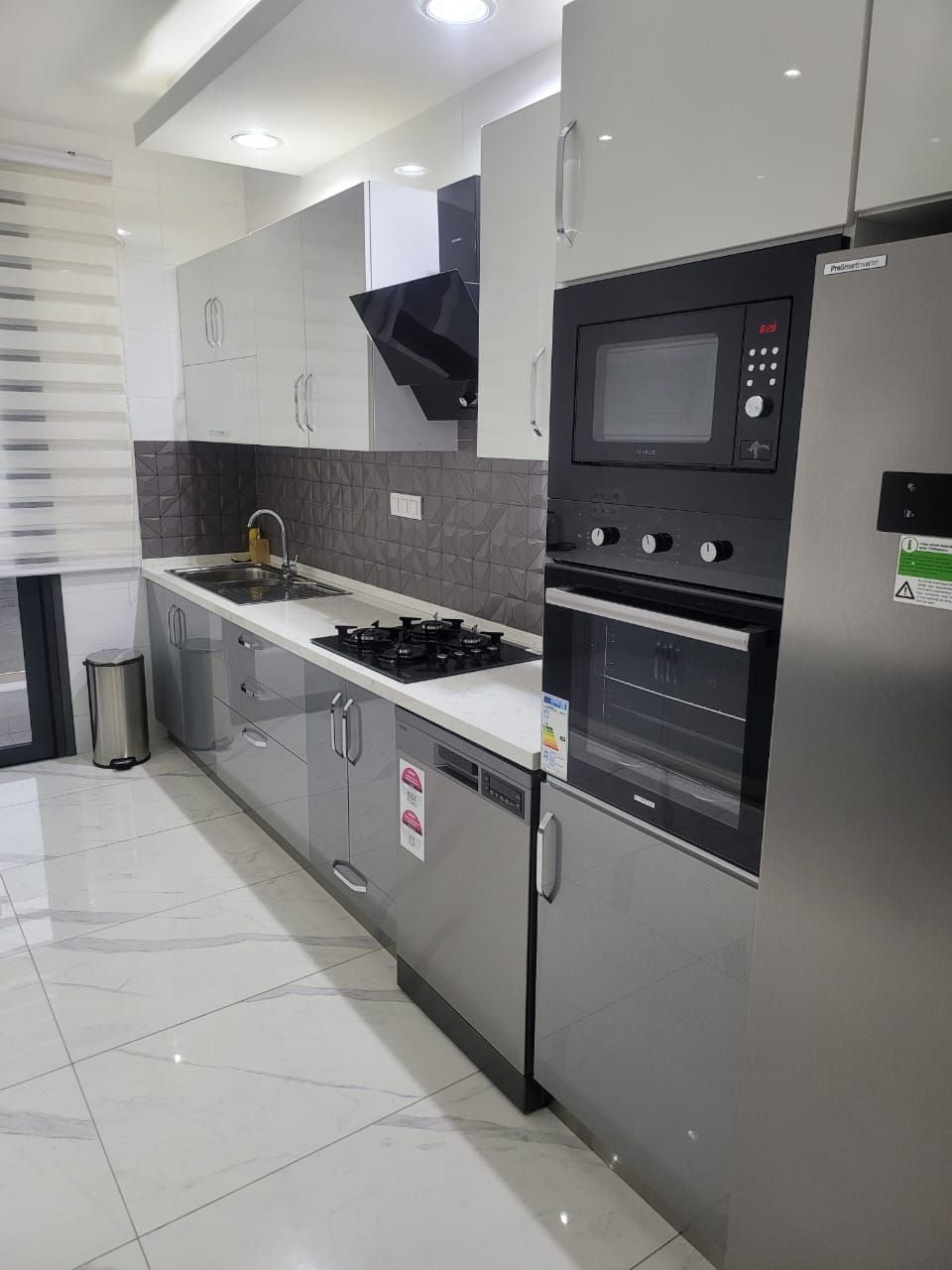 Una cocina moderna con electrodomésticos de acero inoxidable, estufa a gas y horno empotrado.