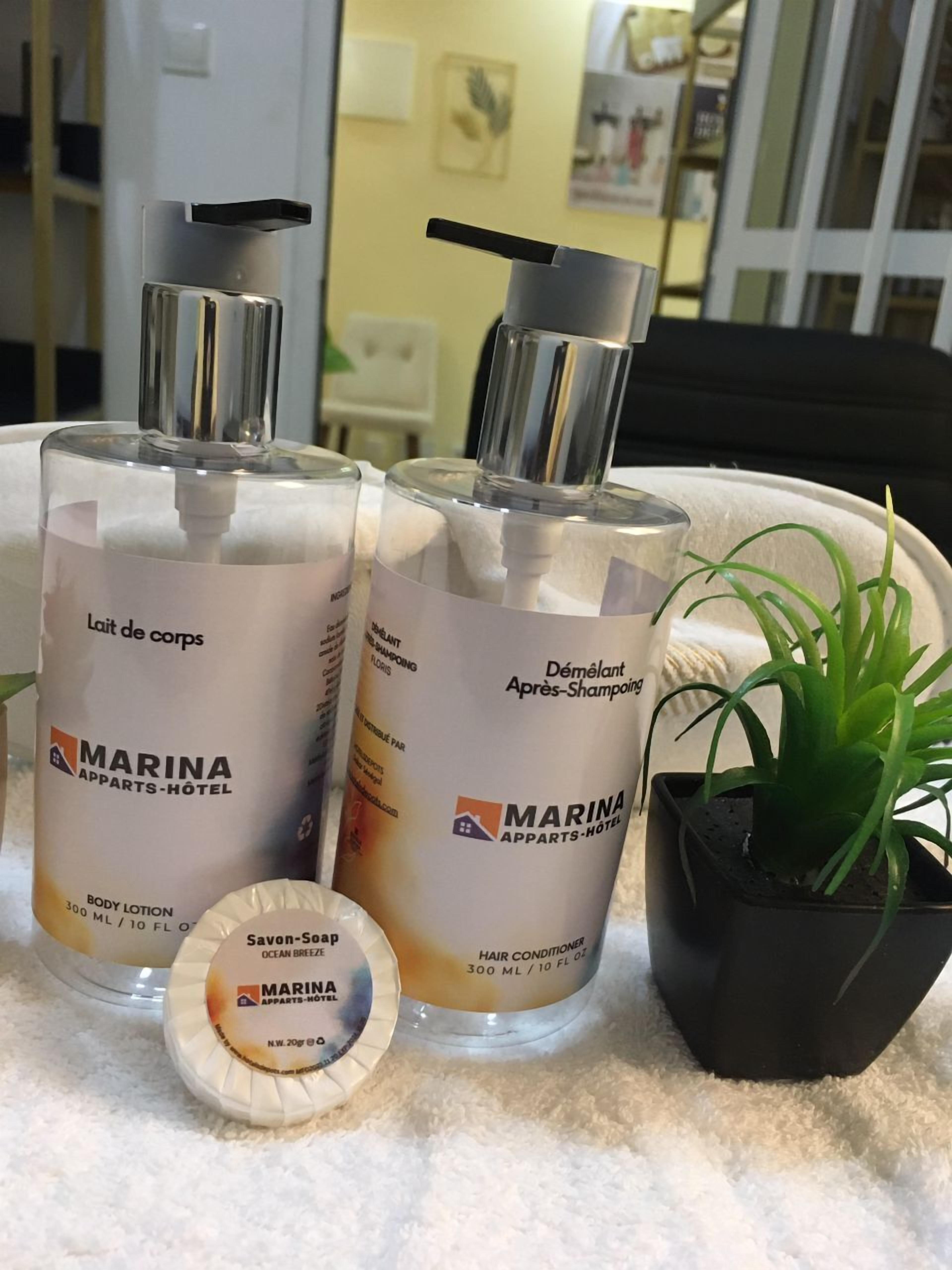 Two Marina body lotion bottles, a hair conditioner bottle, and a soap bar on a white surface.