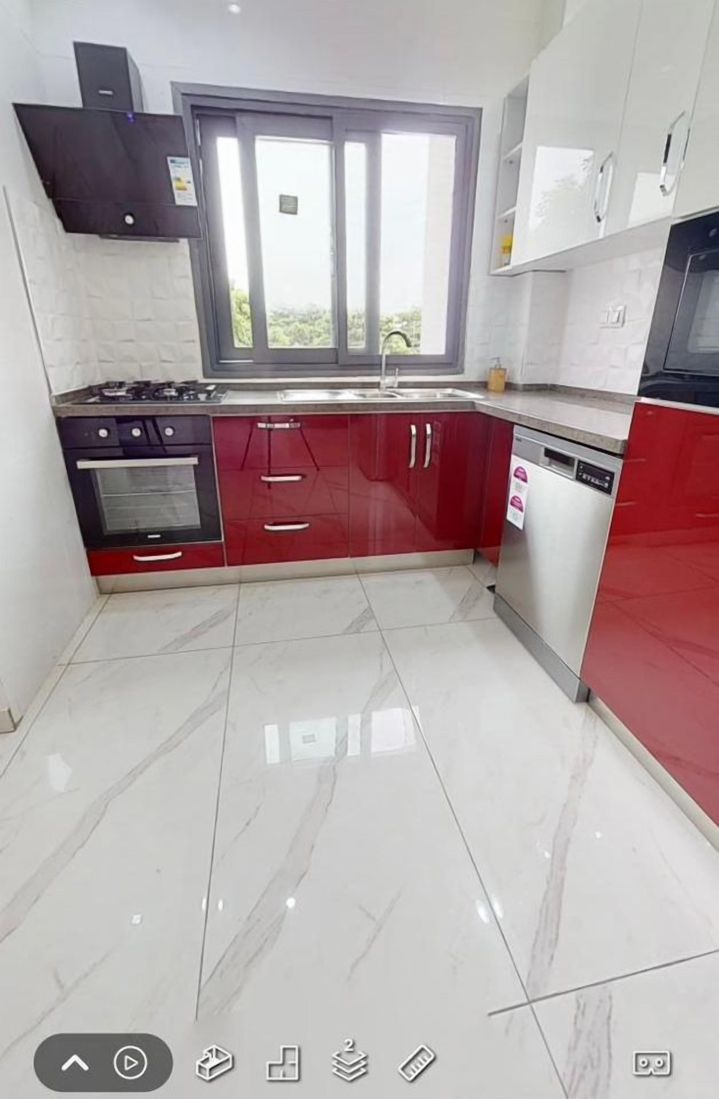 A modern kitchen with a gas stove, oven, red cabinets, and a dishwasher.