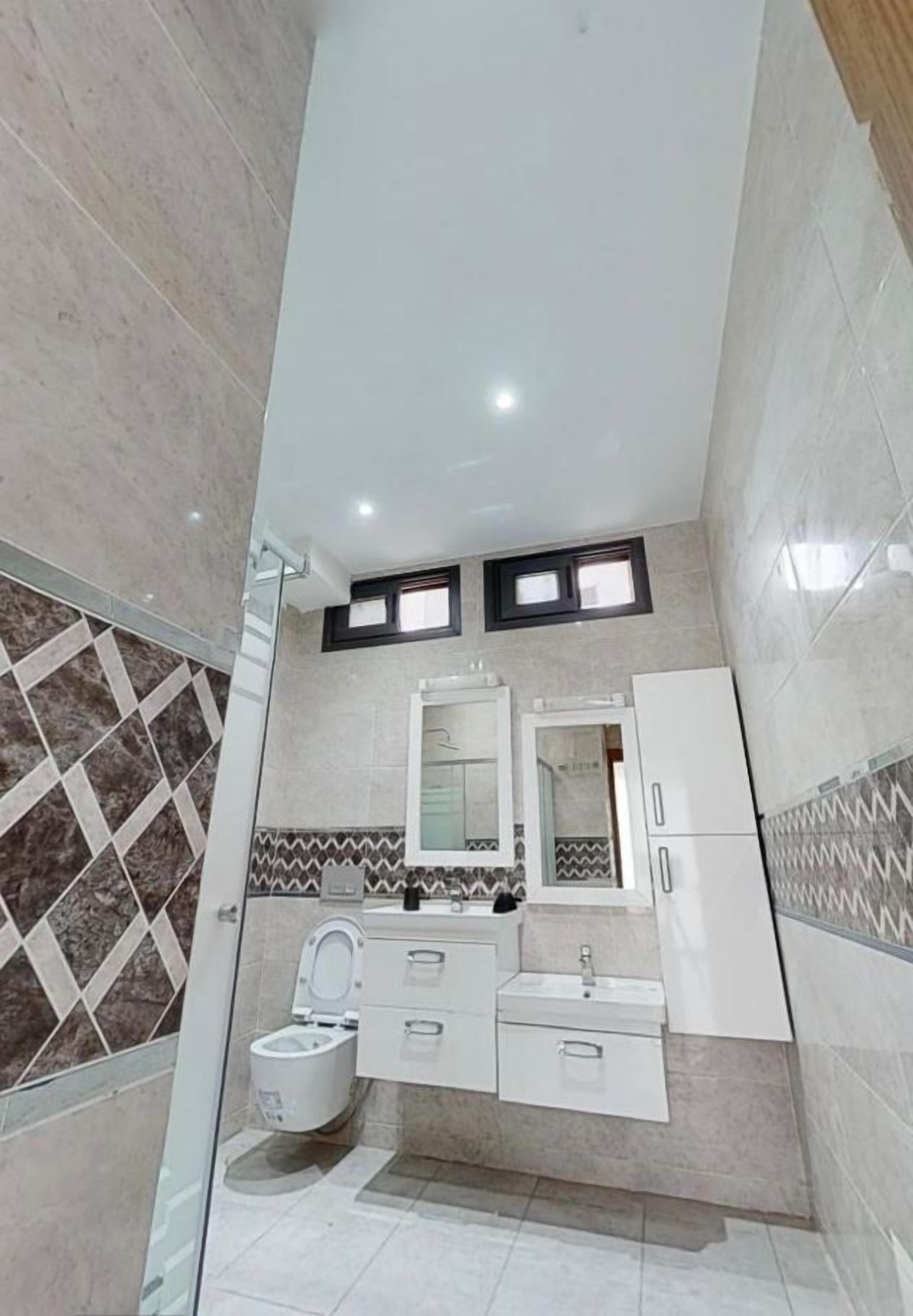 Un baño moderno con inodoro, lavamanos y espejo.