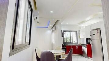 Una cocina moderna con armarios rojos, un refrigerador de acero inoxidable y un comedor con una mesa y sillas.