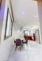 A modern kitchen with red cabinets, a stainless steel refrigerator, and a dining area with a table and chairs.